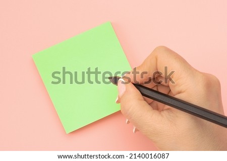 Hand written notes black pencil on green sticker. pink table background. woman hand writing on green sticky notes. Business people meeting and use notes to share idea on sticky note. Royalty-Free Stock Photo #2140016087