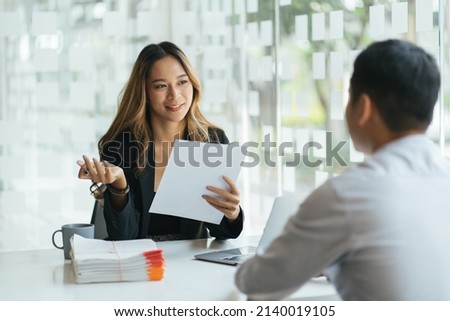 Joyful corporate trainer telling newcomer about work in company. Happy business woman holding tablet and talking to male colleague at meeting table. Newcomer concept