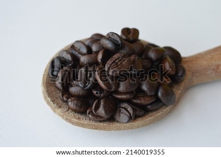 Coffee beans in a wooden spoon isolated on white background