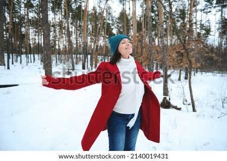 Beautiful happy dark-haired woman having fun, whirling in a snow covered nature, enjoying beautiful cold winter day while walking on a snowy pine forest. Wonderful winter, cool weather Royalty-Free Stock Photo #2140019431