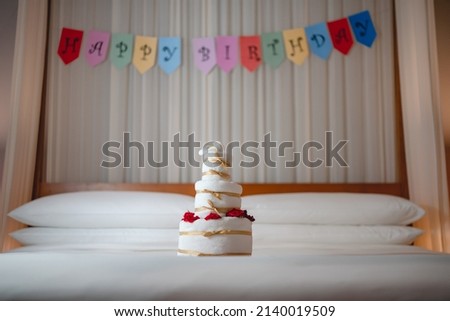 Celebrating Birthday, surprise in bed with Happy birthday banner and towel cake.
