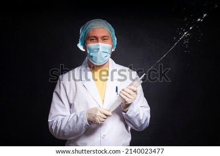 young man dressed as a laboratory assistant with an enema syringe