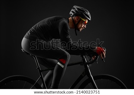 male cyclist riding road bicycle on black background Royalty-Free Stock Photo #2140023751