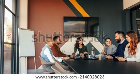 Group of multicultural businesspeople having a meeting in a boardroom. Happy businesspeople having a discussion during their morning briefing. Young entrepreneurs collaborating in a modern office. Royalty-Free Stock Photo #2140028023