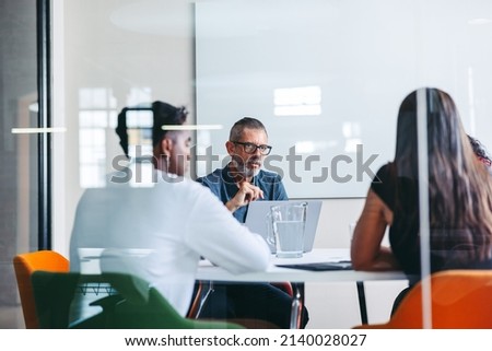Group of businesspeople having a discussion in a meeting room. Experienced mature businessman leading a meeting in a modern office. Group of creative businesspeople working as a team. Royalty-Free Stock Photo #2140028027