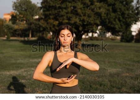 Asian girl does qigong meditation in the green park. Young woman stand in special stance and do special hand movement Royalty-Free Stock Photo #2140030105
