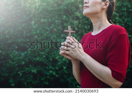 Asian woman praying with wood cross and believe in God