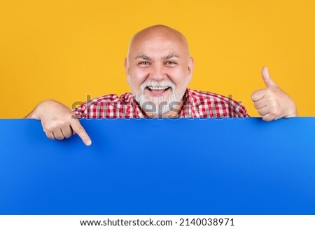 happy senior man with copy space on blank banner. advertising. point finger