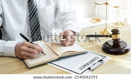 Male lawyer working with litigation contract paper documents of the estate lawsuit, Law books and wooden gavel on table office.