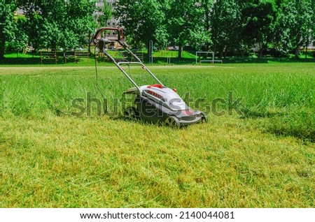 Electric hand lawn mower at stadium. Lawn care on  sports field.