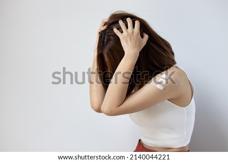 Concept image of anonymous fully vaccinated asian woman getting boosted with the first booster, experiencing headache, fever, adverse event side effect after vaccine booster shot Royalty-Free Stock Photo #2140044221