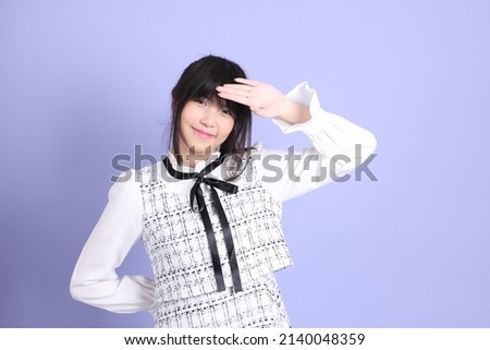 The young Asian girl in white preppy dressed standing on the purple background.