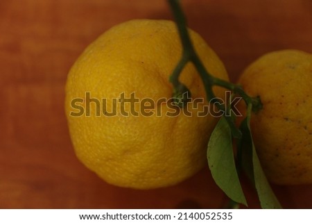 Yellow citrus fruit with green leaf on a brown wooden surface