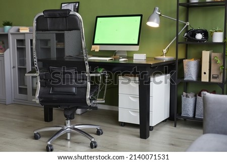 Background image of home office workplace with chroma key computer screen on desk against green wall, copy space