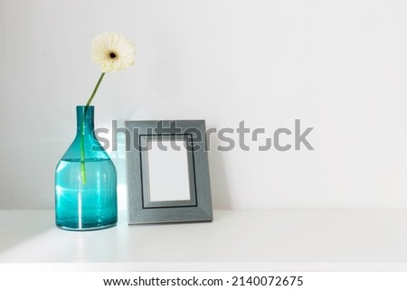 gerber in glass vase and wooden frame on white wooden wall