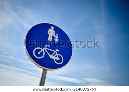 Blue cycle path and foot path sign against a blue sky.