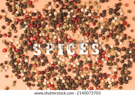 spices written from wooden letters between peppercorns. spices texture and name