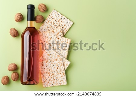Passover celebration concept. Matzah, red kosher wine and walnut. Traditional ritual Jewish bread on light green background. Passover food. Pesach Jewish holiday. Royalty-Free Stock Photo #2140074835