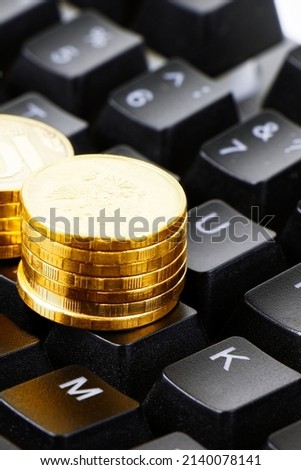 Gold coins and black keyboard isolated on a white background. Work at home. Make maoney.Select focus.Vertical orientation.Freelance concept