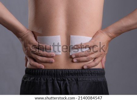 Medicated pain relief patch with man pain Lower Back,office syndrome,Health problems from overworked concept. Royalty-Free Stock Photo #2140084547