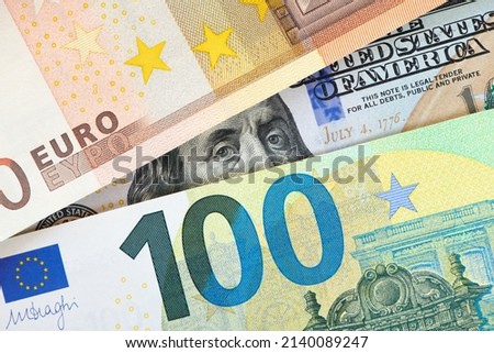 Euro and dollar notes. euro against dollar. A closer look of the president of the USA with a dollar bill, peeping out from behind a euro bill. USA and Europe finance relation. Close up top view. Royalty-Free Stock Photo #2140089247