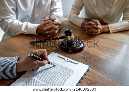 Unhappy divorce couple having conflict, husband and wife during divorce process with senior male lawyer or counselor and couple signing decree of divorce contract in lawyer's office. Royalty-Free Stock Photo #2140092333