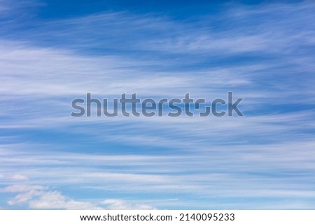 Streaky white clouds in a blue sky on a sunny day Royalty-Free Stock Photo #2140095233