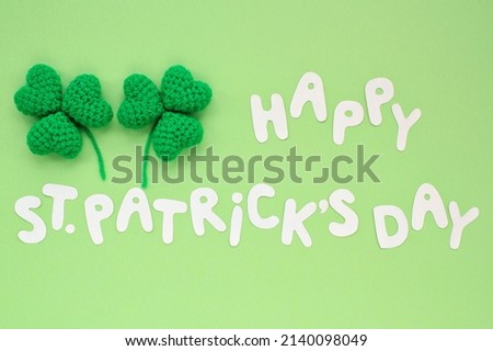 Happy St. Patrick's Day lettering with two shamrock leaves on green background. Flatlay festive concept. Blank for greeting card, advertising flyer. Creative idea for poster, banner, magazine, web