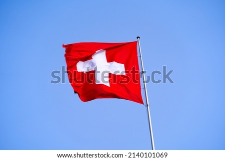 Swiss flag waving on top of building at City of Lausanne on a sunny spring day. Photo taken March 18th, 2022, Lausanne, Switzerland.