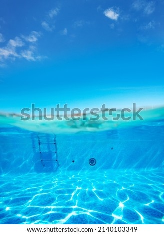 Split underwater pool photo of rails and ladder stairs with sun playing on the floor