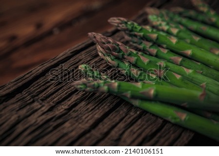 closeup picture of fresh sparrow grass ready for cooking on a textured antique chopping board