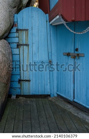 An old blue wooden door next to a rock formation. Picture from the Swedish rock-island town Smogen