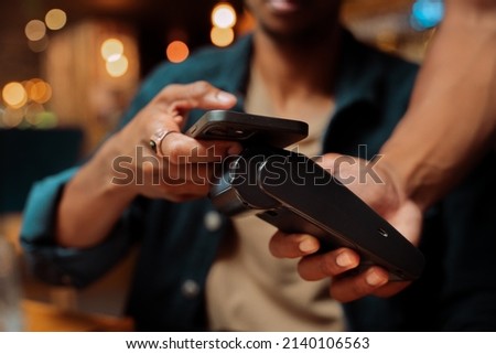 close up of customer paying with cellular device and card machine Royalty-Free Stock Photo #2140106563
