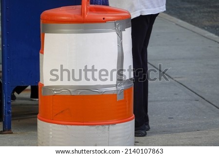 Blank white sign duck taped to an orange traffic warning barrel