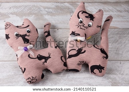Cats made of handmade fabric on a wooden background. Toy for children needlework
