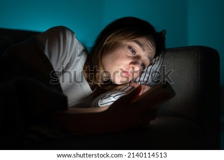 Unhappy woman lying in bed with smartphone, following ex-boyfriend on social media, sad female using mobile phone at night, can not sleep after relationship breakup, suffering from insomnia. Anxiety. Royalty-Free Stock Photo #2140114513