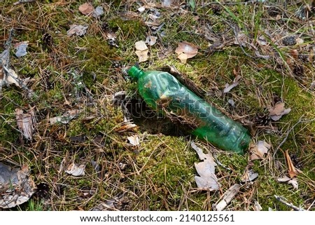 Used disposable green plastic bottle in forest. Pollution environment. Long decaying waste in nature. Royalty-Free Stock Photo #2140125561