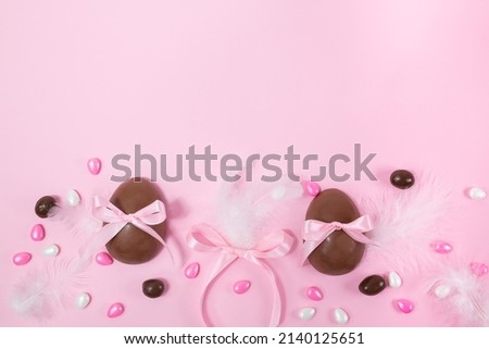 Colorful Easter chocolate eggs, flat lay on pink background. Happy Easter. Stylish Easter layout. Greeting card or banner template. High quality photo