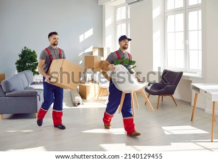 Smiling male carriers or movers unload objects help client with moving at home or office. Deliverymen team work unload belongings during customer relocation. Shipping and delivery service. Royalty-Free Stock Photo #2140129455