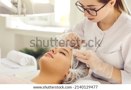 Beautiful lady getting corrective dermal aesthetic improvement treatment and receiving safe forehead youth injection. Skincare professional injecting restylane, sculptra or PRP for perfect face Royalty-Free Stock Photo #2140129477