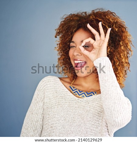 Youre so fine, you blow my mind. Studio shot of a young woman looking through her fingers against a grey background.