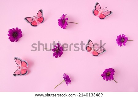 A wallpaper or pattern made of butterflies and spring flowers against pink background. Creative concept for web banner, invitation or phone background