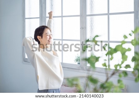 Asian woman stretching with a smile Royalty-Free Stock Photo #2140140023