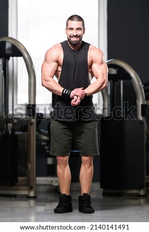 Handsome Young Man Standing Strong In The Gym And Flexing Muscles - Muscular Athletic Bodybuilder Fitness Model Posing After Exercises Royalty-Free Stock Photo #2140141491
