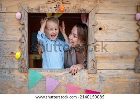 mom and son in bunny ears celebrate easter, play in the playhouse. Happy easter. Royalty-Free Stock Photo #2140150085
