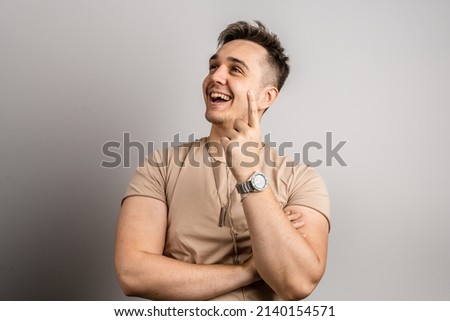Portrait of one adult caucasian man 25 years old looking to the camera in front of white wall background smiling wearing casual t-shirt copy space