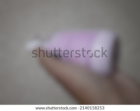Defocused abstract background of a plastic bottle of pink body lotion