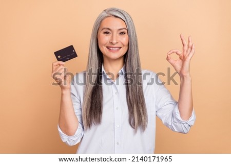 Photo of mature woman show fingers okey symbol recommend credit card perfect select isolated over beige color background