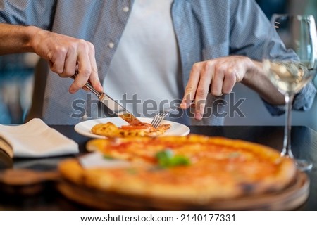 Close up picture of a ma cutting pizza