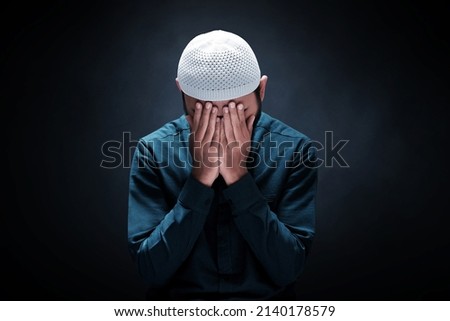 Muslim man praying on dark background Royalty-Free Stock Photo #2140178579